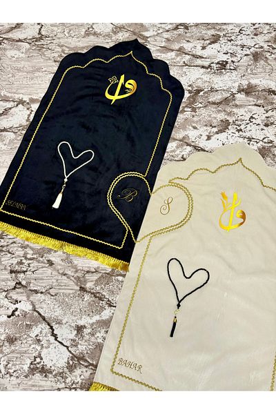 Evince سجادة صلاة على شكل قلب باللون الأسود والكريمي، مع ألياف، وشرابة، ومبطنة، تحتوي على اسم وحرف مطرزين.