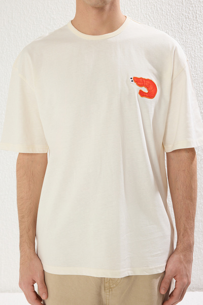 Trendyol Collection Flauschiges T-Shirt in Ecru – Übergröße, Patch-Detail, kurze Ärmel, 100 % Baumwolle TMNSS25TS00029