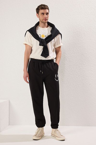 Trendyol Collection Czarne, oversize'owe spodnie dresowe z nadrukiem Smiley Buziak - elastyczna nogawka TMNSS22EA0119