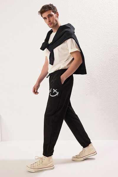 Trendyol Collection Czarne, oversize'owe spodnie dresowe z nadrukiem Smiley Buziak - elastyczna nogawka TMNSS22EA0119