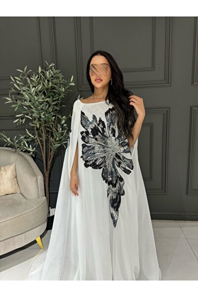 VİVİ A loose white dress with luxurious black and silver embroidery and a flowing cape.