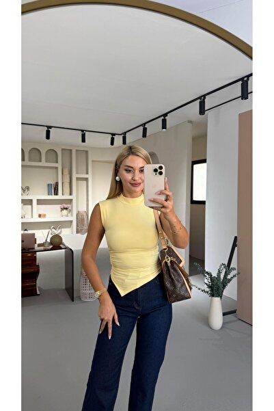 Sezgi Tekin بلوزة ذات ياقة عالية وتفاصيل مطوية باللون الأصفر وقصة غير متماثلة