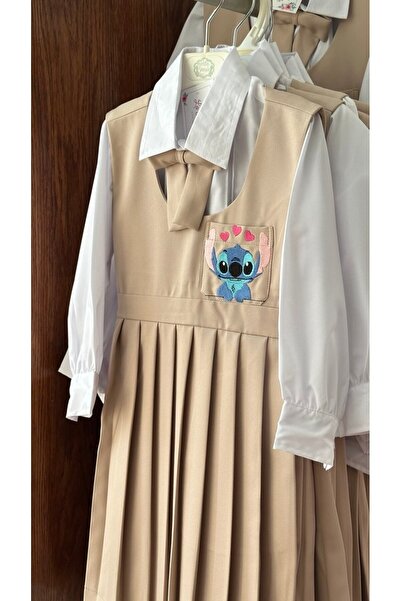 La reina petite Kindergarten pinafore, beige color with Stitch character embroidery, with a white shirt and bow tie.