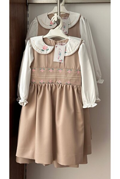 La reina petite Kindergarten pinafore, beige color, one piece, with rose embroidery on the waistband and collar.