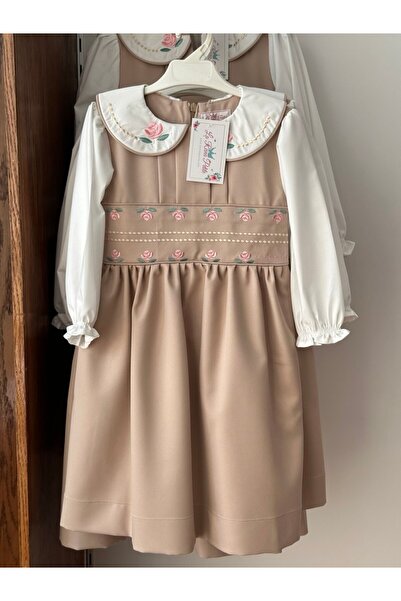 La reina petite Kindergarten pinafore, beige color, one piece, with rose embroidery on the waistband and collar.