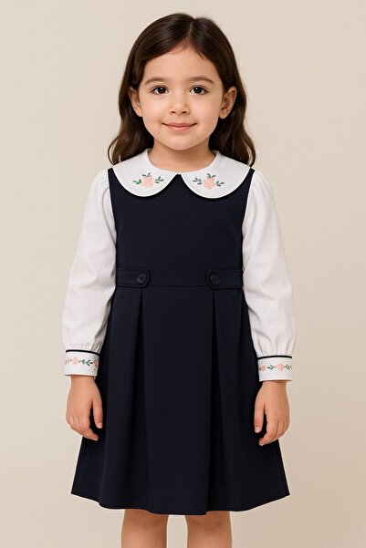 La reina petite Larina Petite kindergarten uniform in navy blue with a white shirt embroidered on the collar and sleeves.