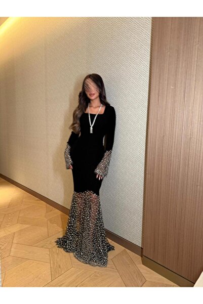 Riva A long black evening dress with embellished sleeves and a sheer, studded train.