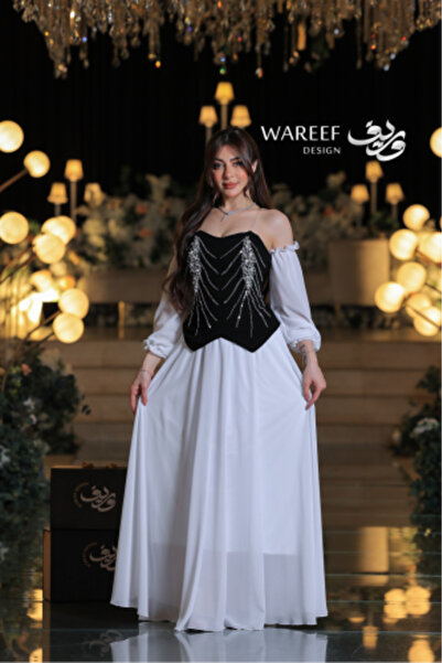 WAREEF FASHION A white dress with a black velvet bodice, puffed sleeves, and shimmering pearl embroidery in a royal corset design.