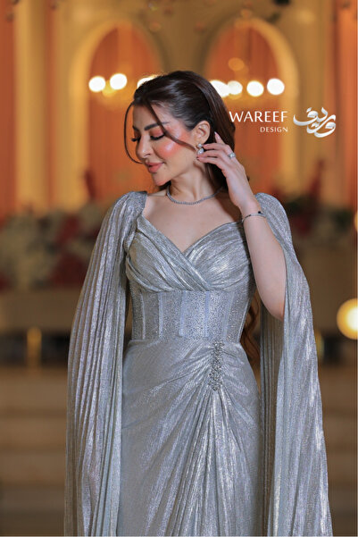 MAC CENTER A shimmering silver evening dress with off-the-shoulder sleeves and an embellished belt.