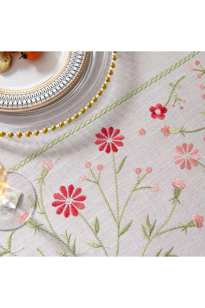 bity thok A luxurious white linen dining tablecloth adorned with a floral design and elegant scalloped edges.