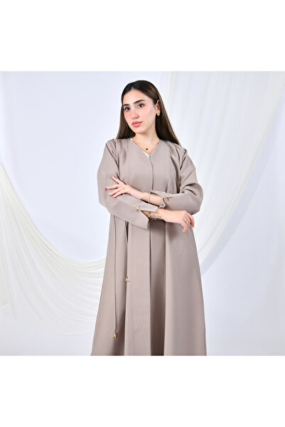 HAWRAA ABAYA عباية بتصميم عصري بلون البيج تزيّنها أزرار ذهبية على شكل نجوم من...