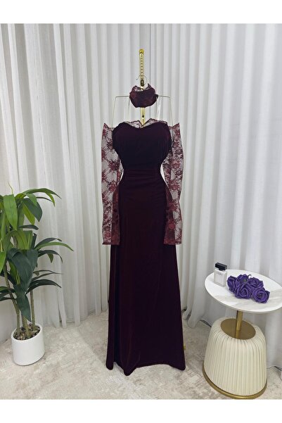 Riva A long, elegant evening dress in burgundy (or reddish-brown). It features a striking and feminine design.