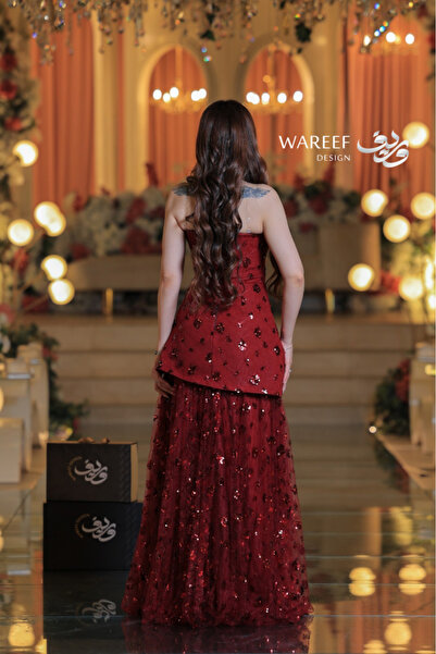 WAREEF FASHION A red evening dress adorned with shimmering embroidery and featuring a plunging neckline.