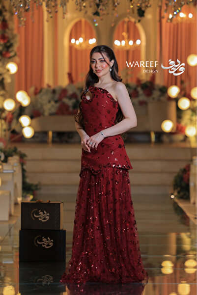 WAREEF FASHION A red evening dress adorned with shimmering embroidery and featuring a plunging neckline.