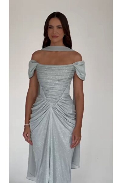 ALFABETA A shimmering evening gown with off-the-shoulder sleeves and an elegant draped silhouette, paired with a shawl.