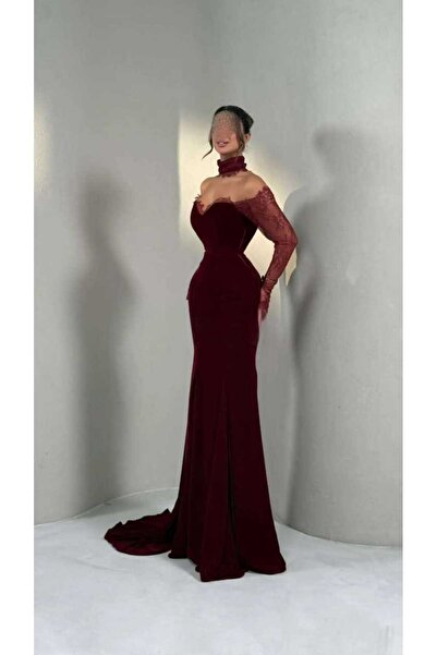 Riva A long, elegant evening dress in burgundy (or reddish-brown). It features a striking and feminine design.