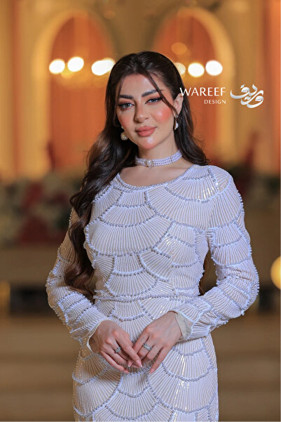 WAREEF FASHION An off-white evening dress with pearl stones and delicate embroidery.