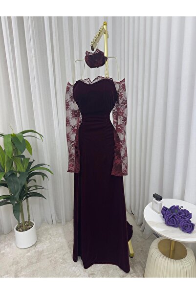 Riva A long, elegant evening dress in burgundy (or reddish-brown). It features a striking and feminine design.