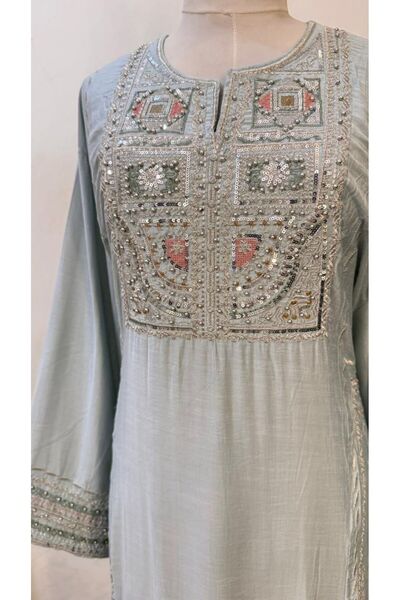 ISHRAQAT AL-AMAL A long, light blue jalabiya with rich embroidery on the chest and sleeves, creating a beautiful drape, perfect for gatherings and special occasions.