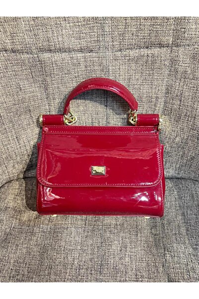Generic A small, glossy handbag in a captivating cherry red color; a classic and attractive design that adds a touch of luxury and elegance to your look.