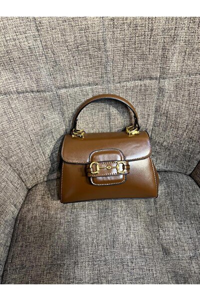 Generic A small brown (dark camel) handbag with a top handle, a classic design adorned with a luxurious gold buckle. A touch of sophistication.