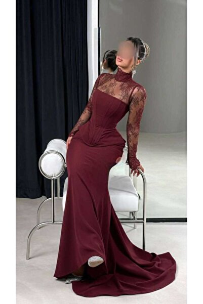 Riva A long, fitted burgundy (or dark burgundy) evening dress, designed to accentuate the figure in a feminine way.