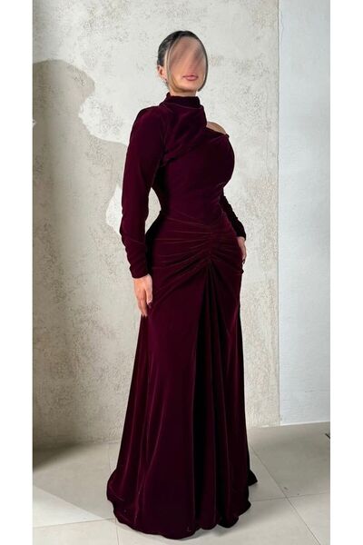 rovan فستان مخمل عنابي فاخر، بكتف مكشوف وياقة مرتفعة، مع ثنيات درابيه تبرز الخصر وقصة طويلة.