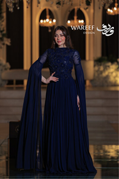 WAREEF FASHION A long, elegant, royal blue evening dress with sheer, embellished sleeves.