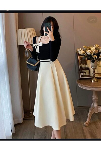 Riva An elegant dress combining black and beige (or off-white) in a classic a...