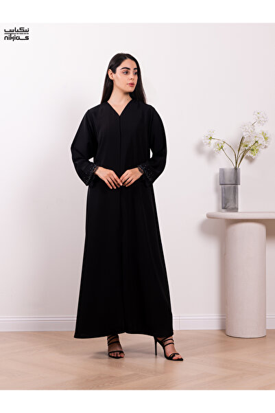 Nikias عباية أنيقة من قماش الكوبرا الكريب، تتميز بتطريزات دانتيل رائعة وتطريز...