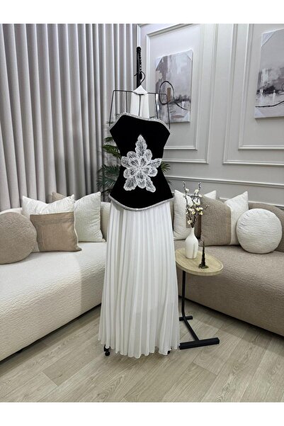 FASHION طقم أنيق يتكون من بلوزة سوداء مخملية بزهرة بيضاء وتنورة بيضاء مكسرة.