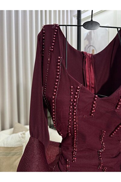 FASHION A long burgundy dress adorned with prominent roses at the waist, feat...