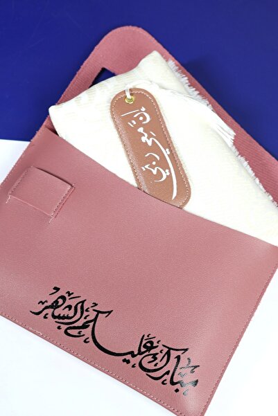 casing A pink gift Bag containing a white prayer mat and a leather divider th...
