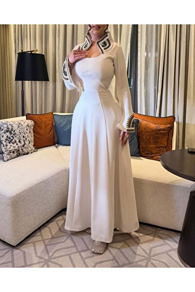 FASHION تفاصيل ياقة وأكمام فستان أبيض، مزينة بتطريزات فاخرة من الأحجار الملونة.