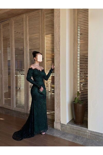 REVE فستان دانتيل زمردي فاخر، بأكتاف مكشوفة وقصة سمكة تبرز الأناقة.