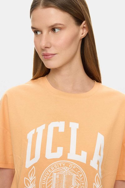 UCLA تي شيرت نسائي فضفاض من القطن بنسبة 100% مطبوع عليه AVALON باللون البرتقالي الفاتح
