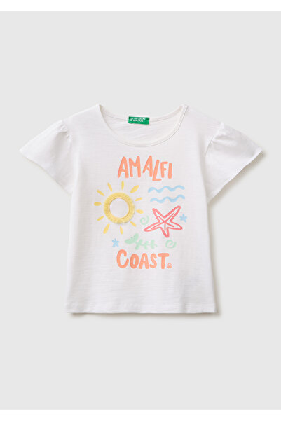 United Colors of Benetton فتاة ترتدي تي شيرت أبيض بطبعات وتفاصيل شرابة بقصة ع...