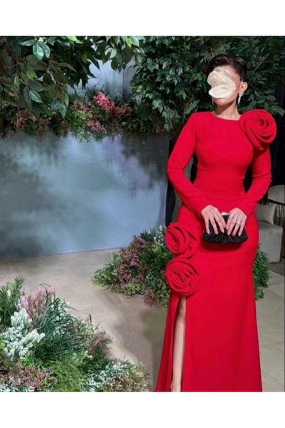 SERENE DRSSE The Picture Shows a Woman Exuding Elegance in a Red Dress, Attracting Attention with Its Unique Design and Floral Embellishments. The Dress Features a Slim Fit That Accentuates the Beauty of the Figure, with Large Pink Details on the Shoulder and Hem.