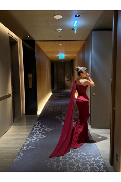 Ayaen فستان سهرة عنابي بكرسيه، درابيه أنيق، وشال كتف واحد منسدل.