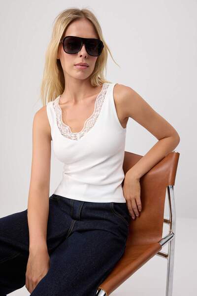 Trendyol Collection قميص داخلي محبوك بدون أكمام وياقة على شكل V بلون إكرو، مر...