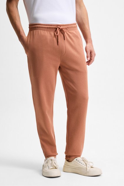 Olsen men's relaxed fit brick red tracksuit with elastic waistband, drawstring, side pockets, and decorative felt appliqués on the back.