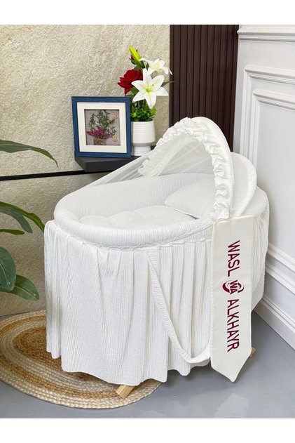 A stylish and safe baby Moses basket crib made of sturdy iron and high-quality off-white fabric with an X base.