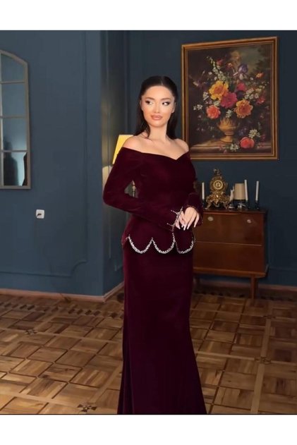 فستان سهرة مخملي طويل عنابي اللون بقصة أفل شولدر (Off-Shoulder) وتفاصيل براقة عند الأطراف
