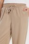 Women's relaxed fit beige trousers with drawstring waist, elasticated waistband, button detail, and double pockets. - 5