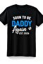 تي شيرت أسود فريد للأبديع المحظوظين بتصميم 'SOON to BE' بخط أبيض منحني وخط 'DADDY' أزرق فاتح بارز بملمس مميز وخط 'Again' أنيق بخط يدوي وتصميم بصمات أقدام الطفل وتصميم 'EST 2Retro Casual'. - 2