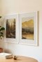 2 VINTAGE PAINTINGS WITH WHITE WOODEN FRAMES FEATURING NOSTALGIC SEPIA-TONED FOREST AND MOUNTAIN SCENES - 3