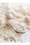 Evening dress shoes with a white bow detail, glittery sand-colored design, single-strap construction, and high heels