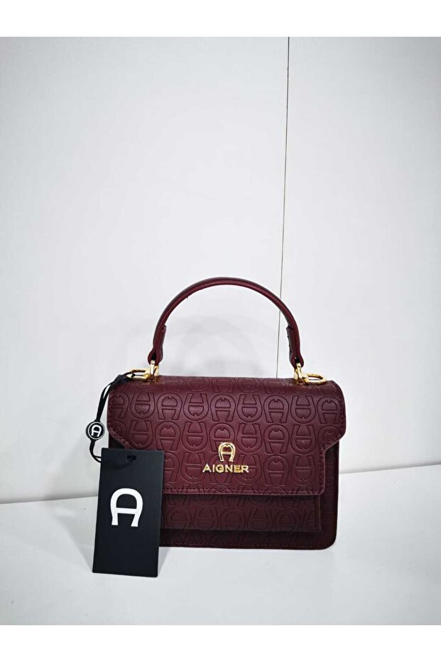 A small burgundy handbag with a subtle pattern and a short top handle. - 1