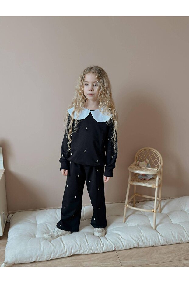 Girl's elegant black two-piece set with stone and pearl detail, featuring a peter pan collar top and bottom.