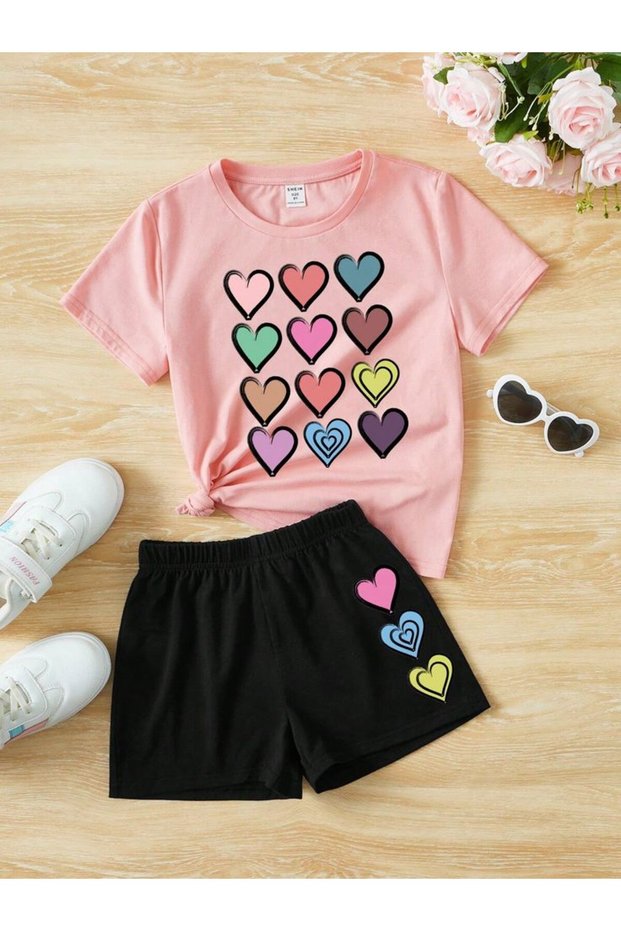 Summer pink t-shirt with multiple heart print, black shorts with heart print.